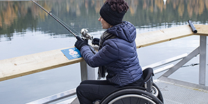 A wheelchair user fishing at the side of a lake within the CRD.