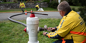Three staff in high-viz gear work at a hydrant as part of the CRD's regular water main flushing program.