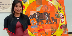 An artist stands in front of her mosaic tile artwork project for Truth and Reconciliation.
