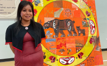 An artist stands in front of her mosaic tile artwork project for Truth and Reconciliation.